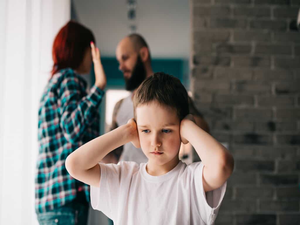 Child Holding Ears in Front of Fighting Parents